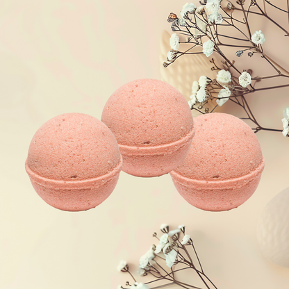 Three pink bath bombs with white flowers on a beige background
