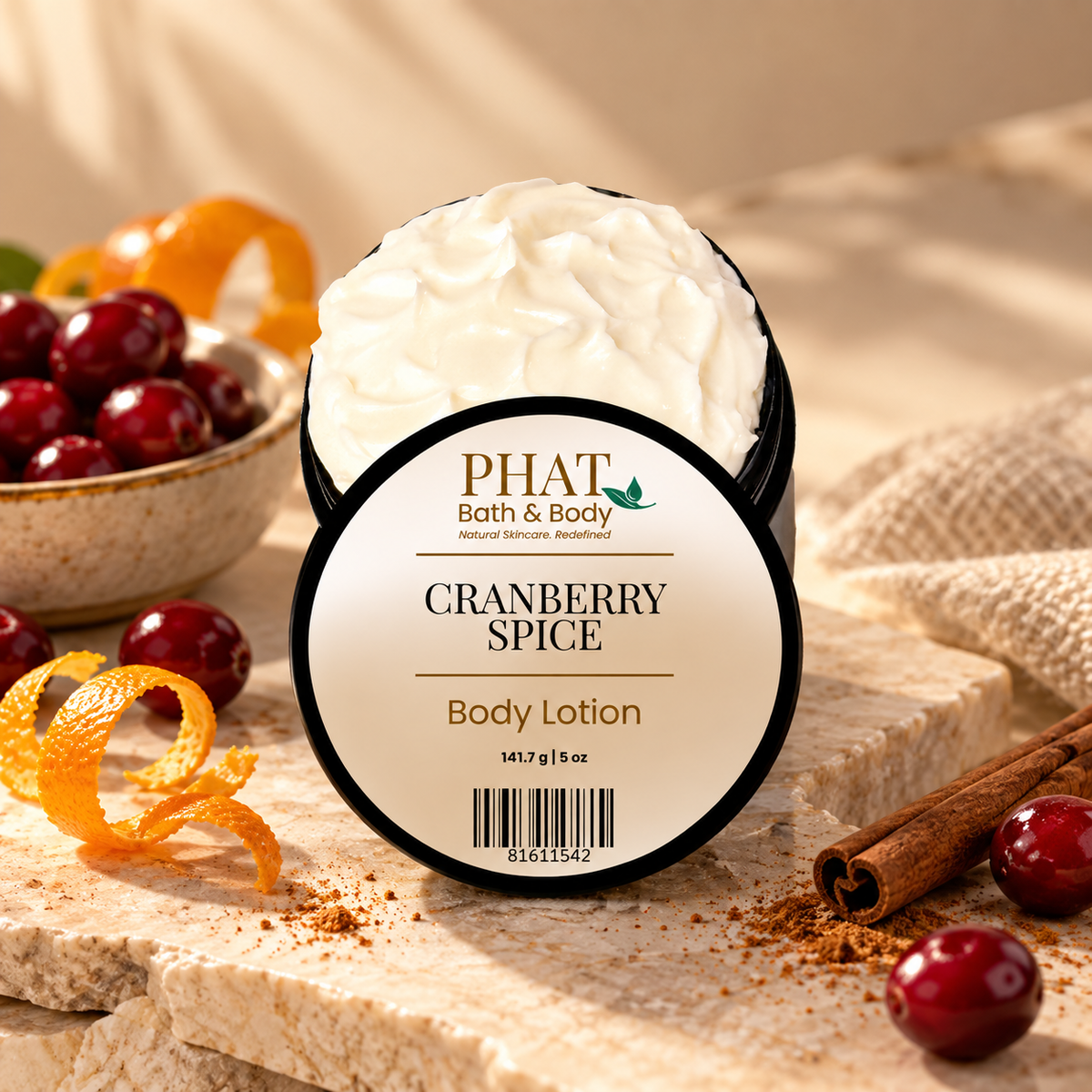 Phat Bath & Body Cranberry Spice Body Lotion with labeled lid displayed among cranberries, orange peel, cinnamon sticks, warm spices, and soft neutral textures.