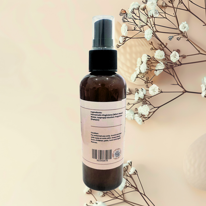 Brown spray bottle with a label on a beige background with white flowers.