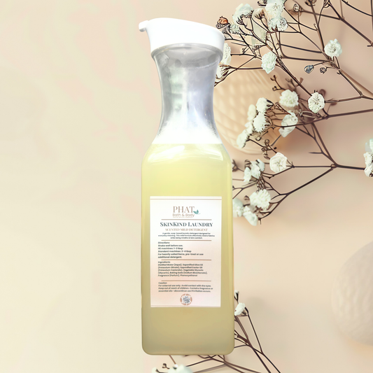 Bottle of Skinkind laundry detergent with a label, surrounded by white flowers on a beige background