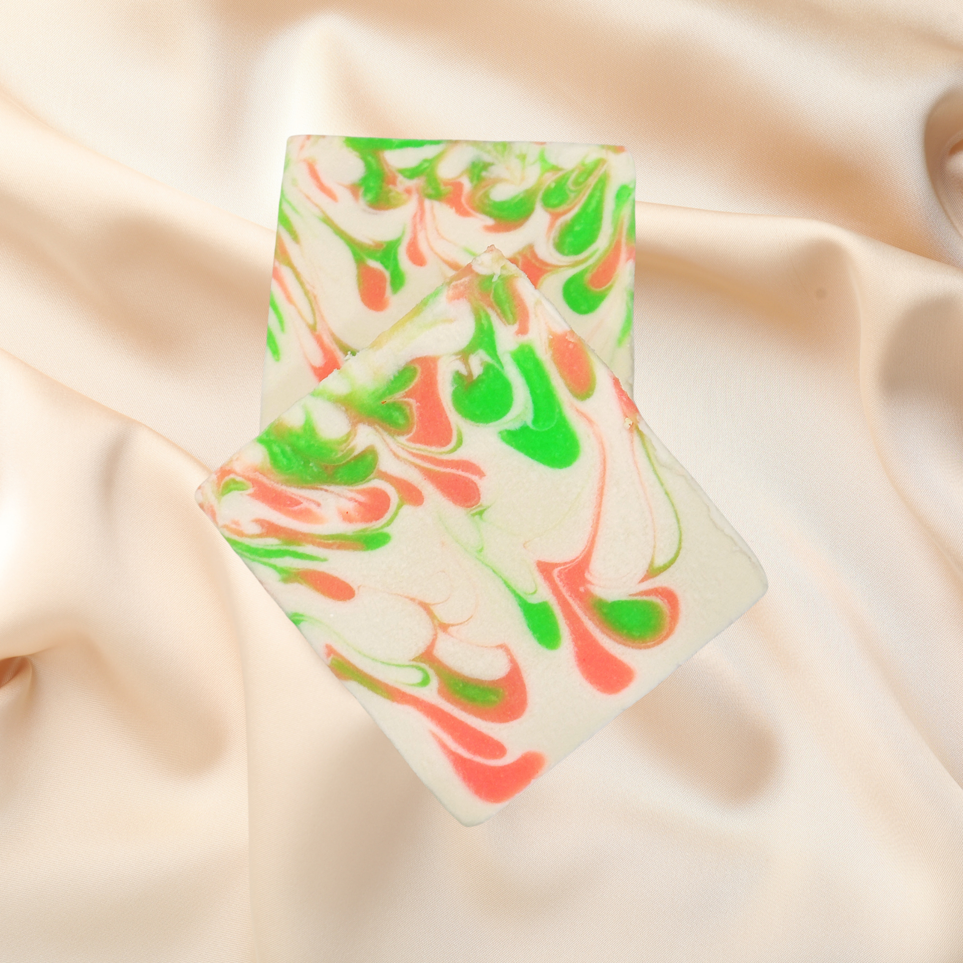 Marbled soap bar with green and pink swirls on a beige fabric background