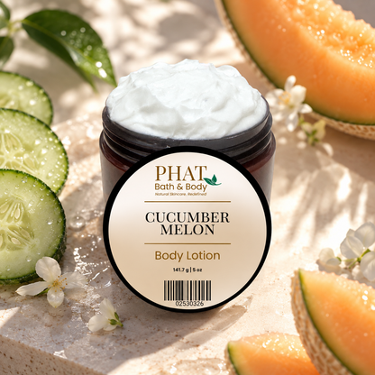 Phat Bath & Body Cucumber Melon 5 oz Body Lotion in an open jar with labeled lid, surrounded by crisp cucumber, fresh-cut melon, white flowers, and soft neutral stone.