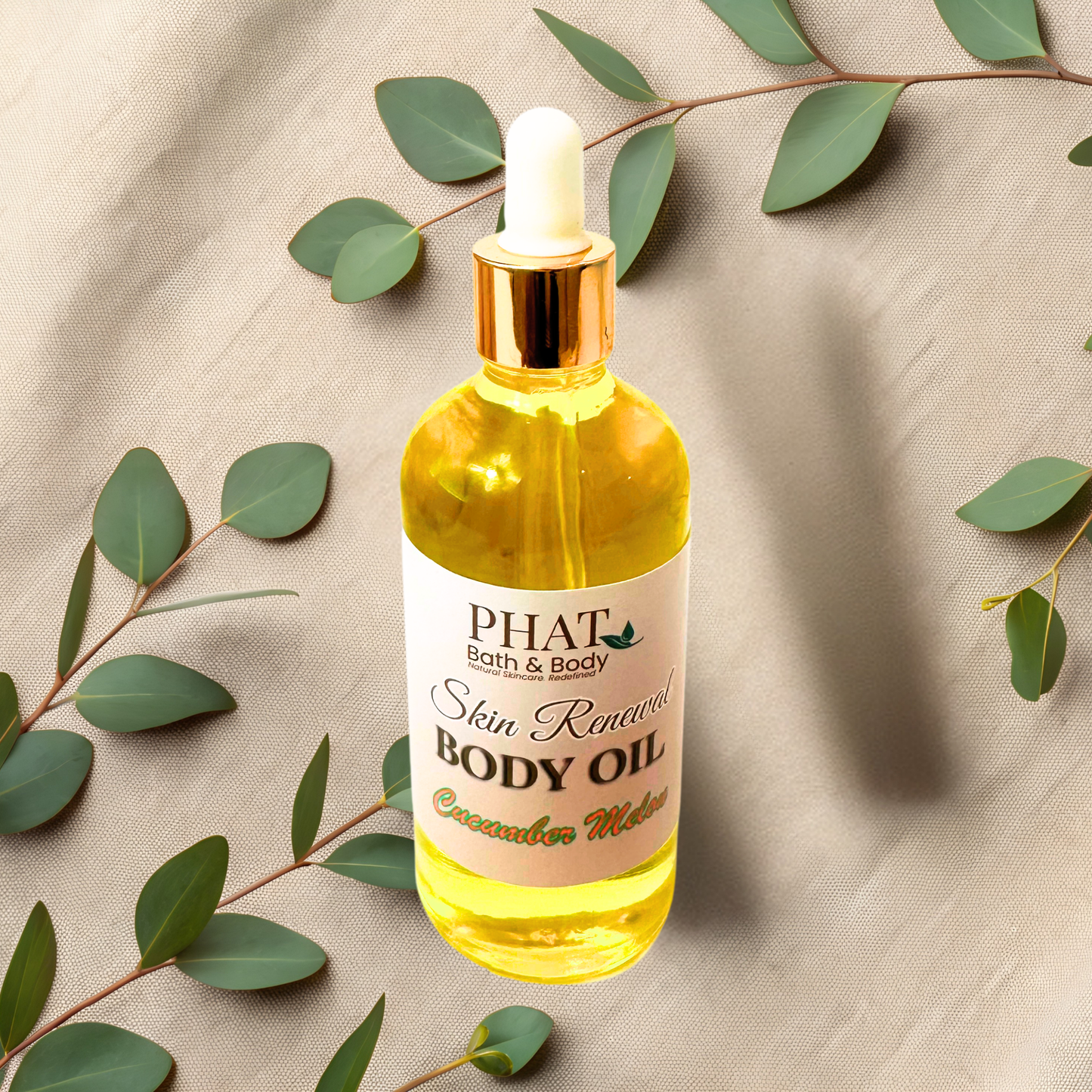 Bottle of PHAT Bath & Body body oil with a dropper on a beige fabric background with green leaves.
