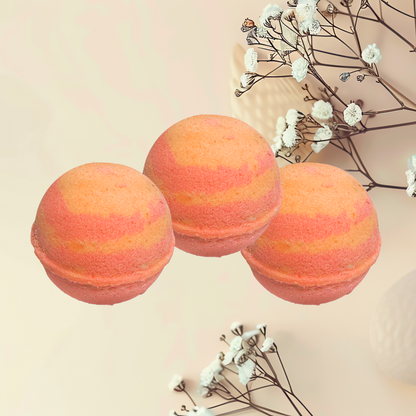 Three striped orange and pink bath bombs on a light beige background with white flowers.