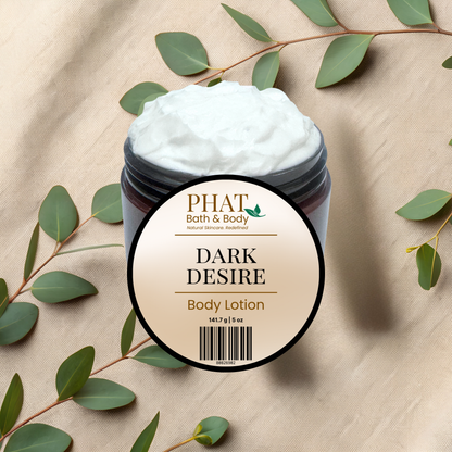 A jar of PHAT Bath & Body 'Dark Desire' body lotion with white cream, styled on a beige textured fabric background with green eucalyptus leaves.