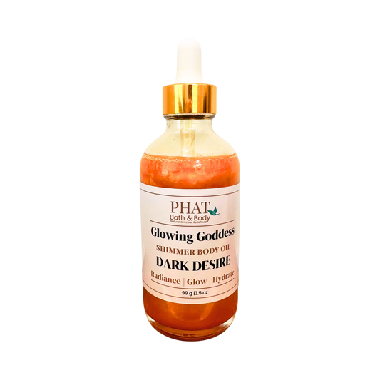 A glass bottle of PHAT Bath & Body 'Glowing Goddess' shimmer body oil in the 'Dark Desire' scent, featuring an amber-colored liquid, a white label, and a gold collar with a white dropper cap, set against a plain white background.