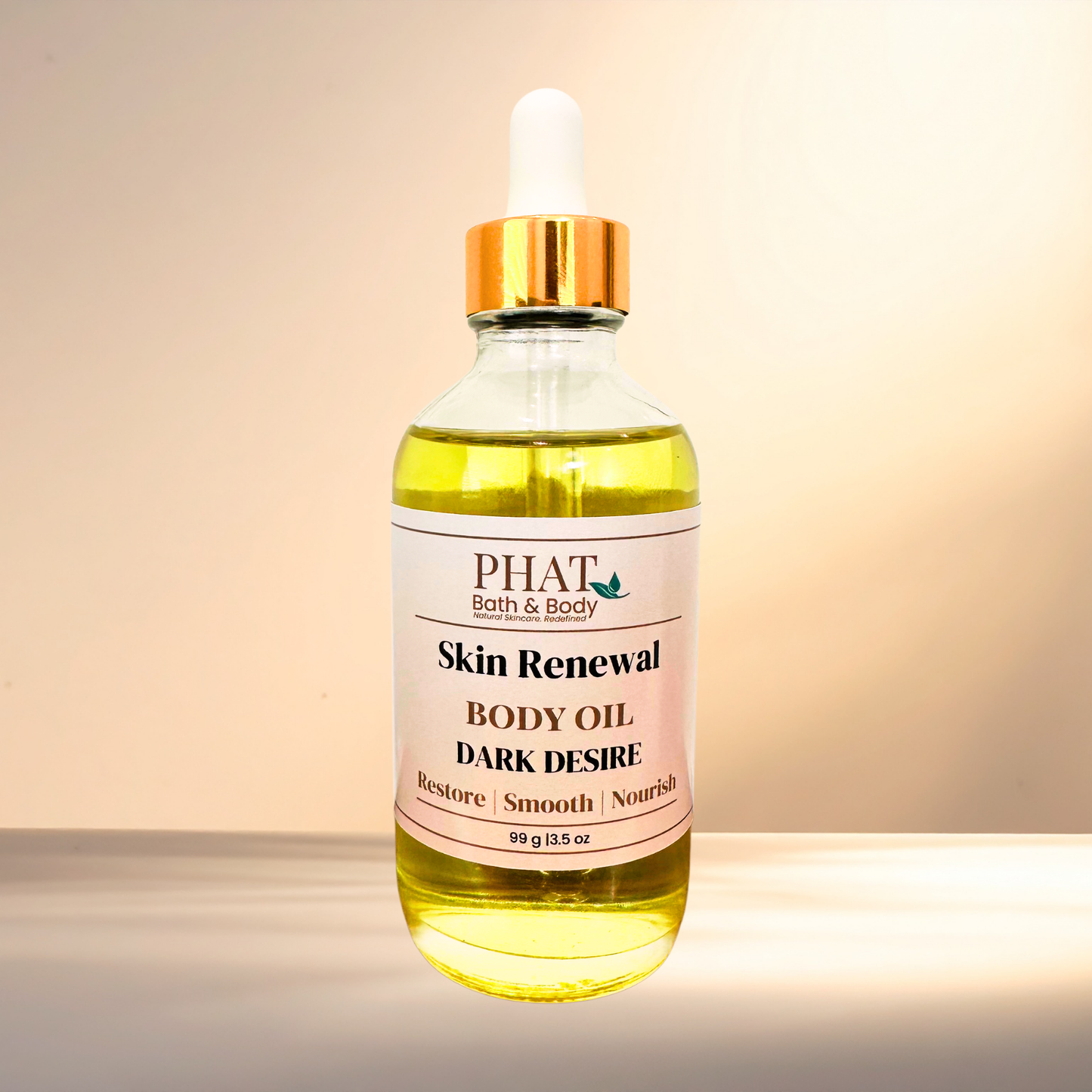A bottle of PHAT Bath & Body Skin Renewal Body Oil with 'Dark Desire' scent, featuring a clear glass bottle filled with yellow oil, a white dropper cap with a gold collar, and a white label, set against a warm beige background.