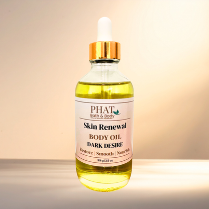 A bottle of PHAT Bath & Body Skin Renewal Body Oil with 'Dark Desire' scent, featuring a clear glass bottle filled with yellow oil, a white dropper cap with a gold collar, and a white label, set against a warm beige background.