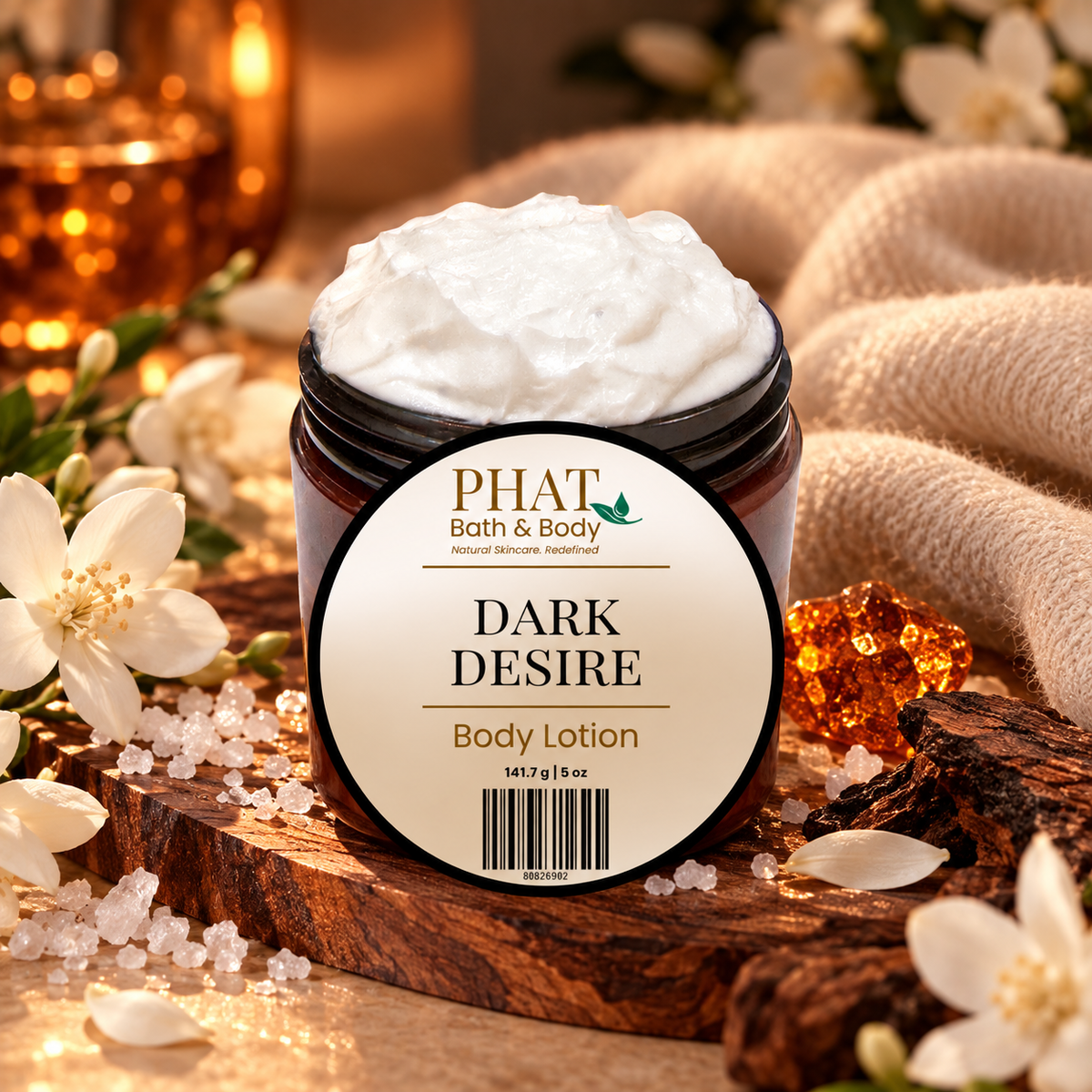 Phat Bath & Body Dark Desire 5 oz Body Lotion with labeled lid, styled with white florals, sea salt, warm woods, amber accents, and soft cashmere-like fabric.