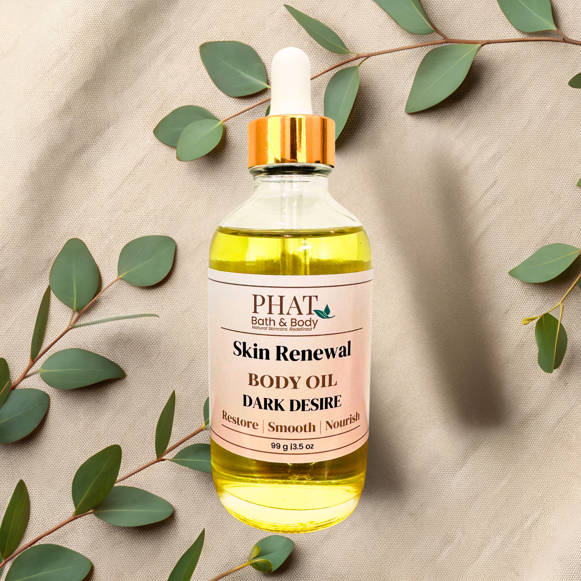 A bottle of PHAT Bath & Body 'Skin Renewal' body oil with a gold cap and white dropper, filled with yellow oil, styled on a beige fabric background with eucalyptus leaves.