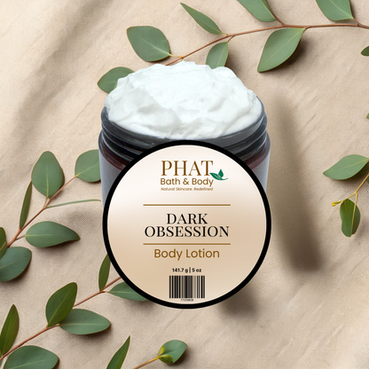 Jar of Dark Obsession body lotion with a 'Phat Bath & Body' label on a beige fabric background with green leaves.