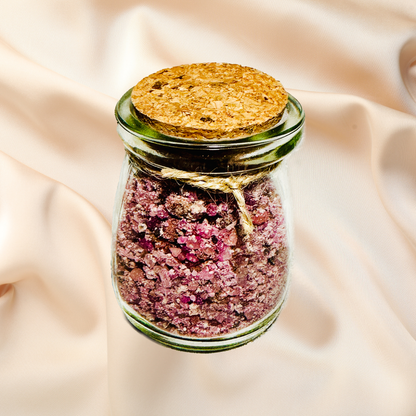 Glass jar with purple bath salts and cork lid on a beige fabric background