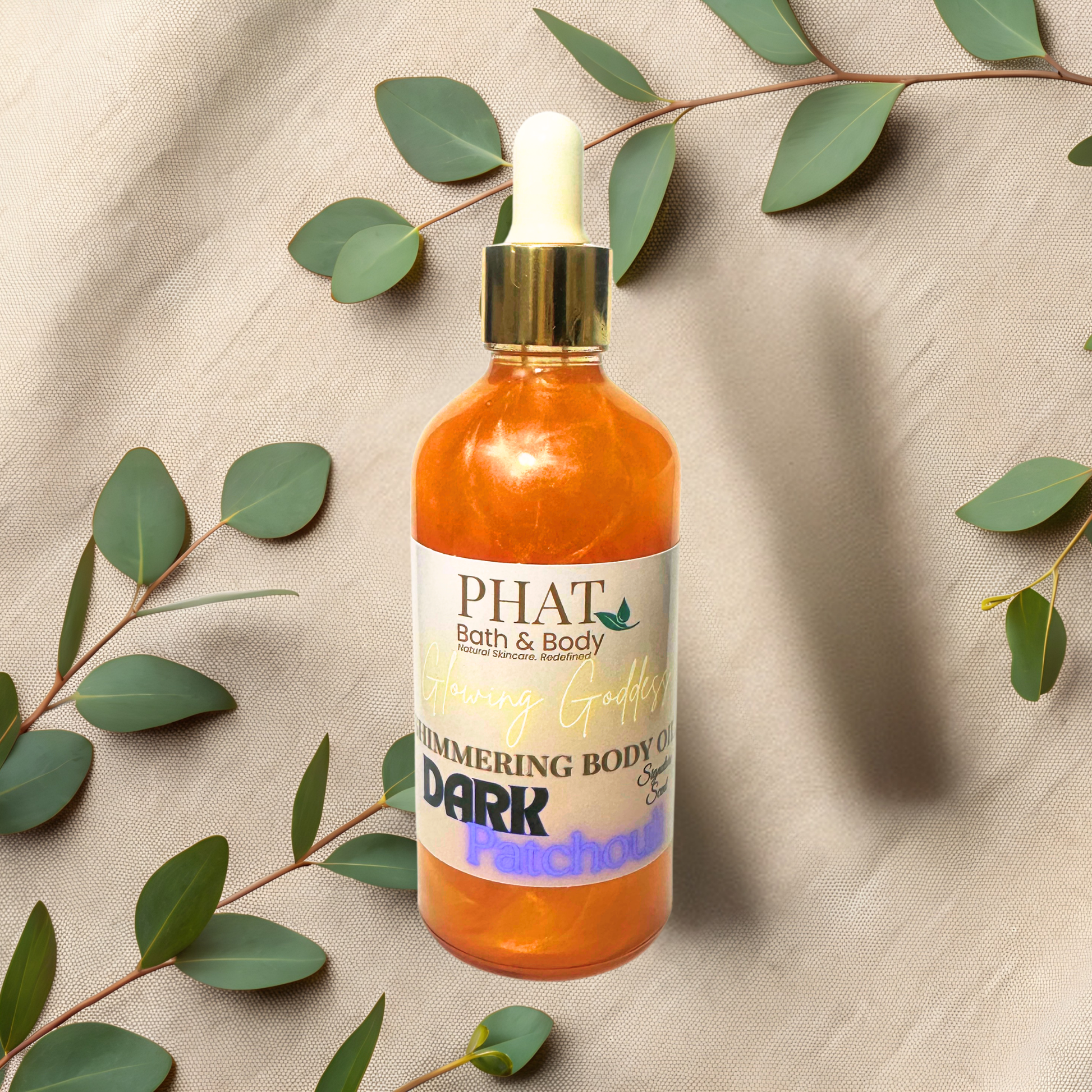 Bottle of 'PHAT Bath & Body' shimmering body oil with green leaves on a beige fabric background