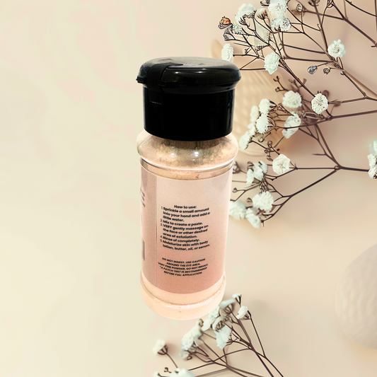 Bottle with black cap and pink label on a beige background with white flowers.