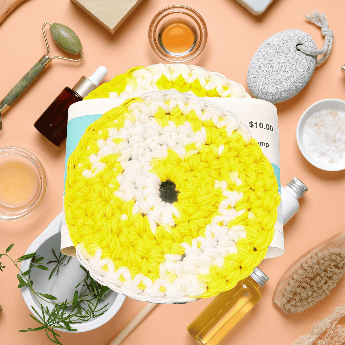 Yellow and white crocheted scrubby with various items on a peach background