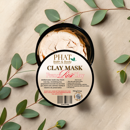 Clay mask container with 'Phat Bath & Body' branding on a beige fabric background with green leaves.