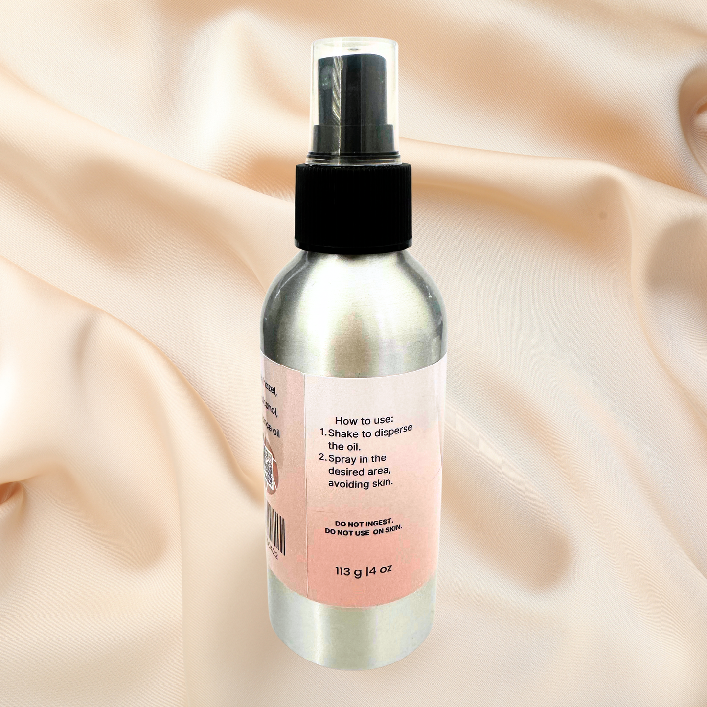 Room spray bottle with a pink label on a beige fabric background