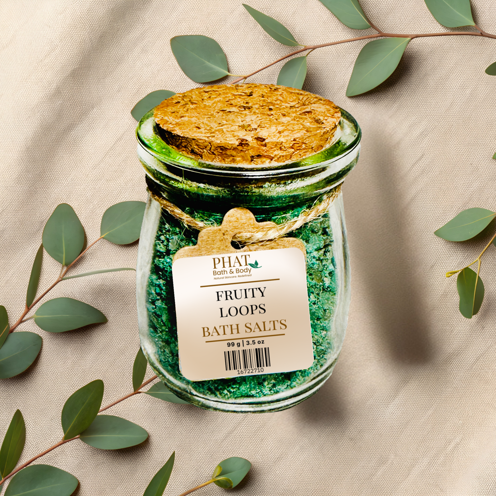 Jar of 'Fruity Loops' bath salts with a cork lid on a beige fabric background with eucalyptus leaves.