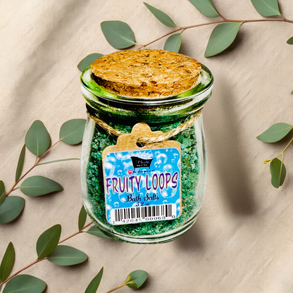 Jar of Fruity Loops bath salts with a decorative label on a beige fabric background with green leaves.