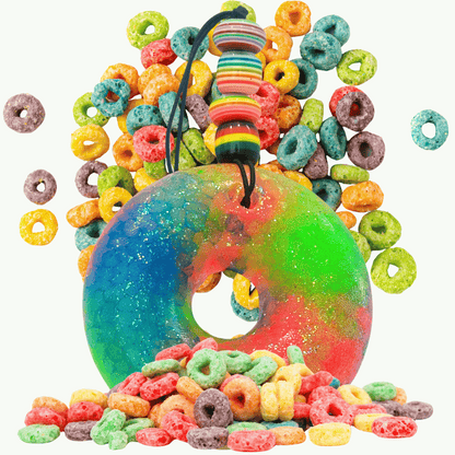 Colorful fruit loop-shaped car freshie with a string surrounded by assorted colorful cereal pieces on a white background
