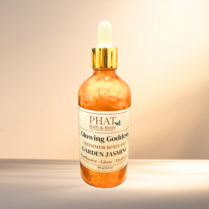 Bottle of 'Glowing Goddess' shimmer body oil from PHAT Bath & Body on a gradient background