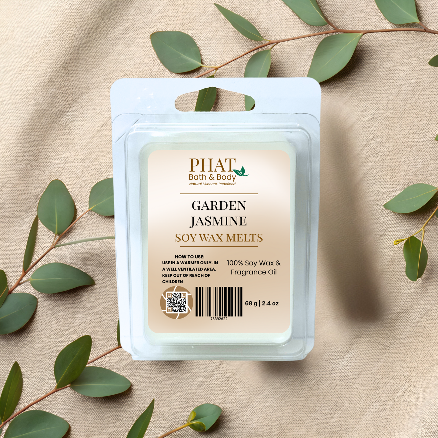 PHAT Bath & Body Garden Jasmine soy wax melts packaging on a beige fabric background with green leaves.