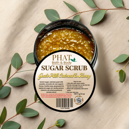 PHAT Bath & Body sugar scrub container with label on a beige fabric background with green leaves.