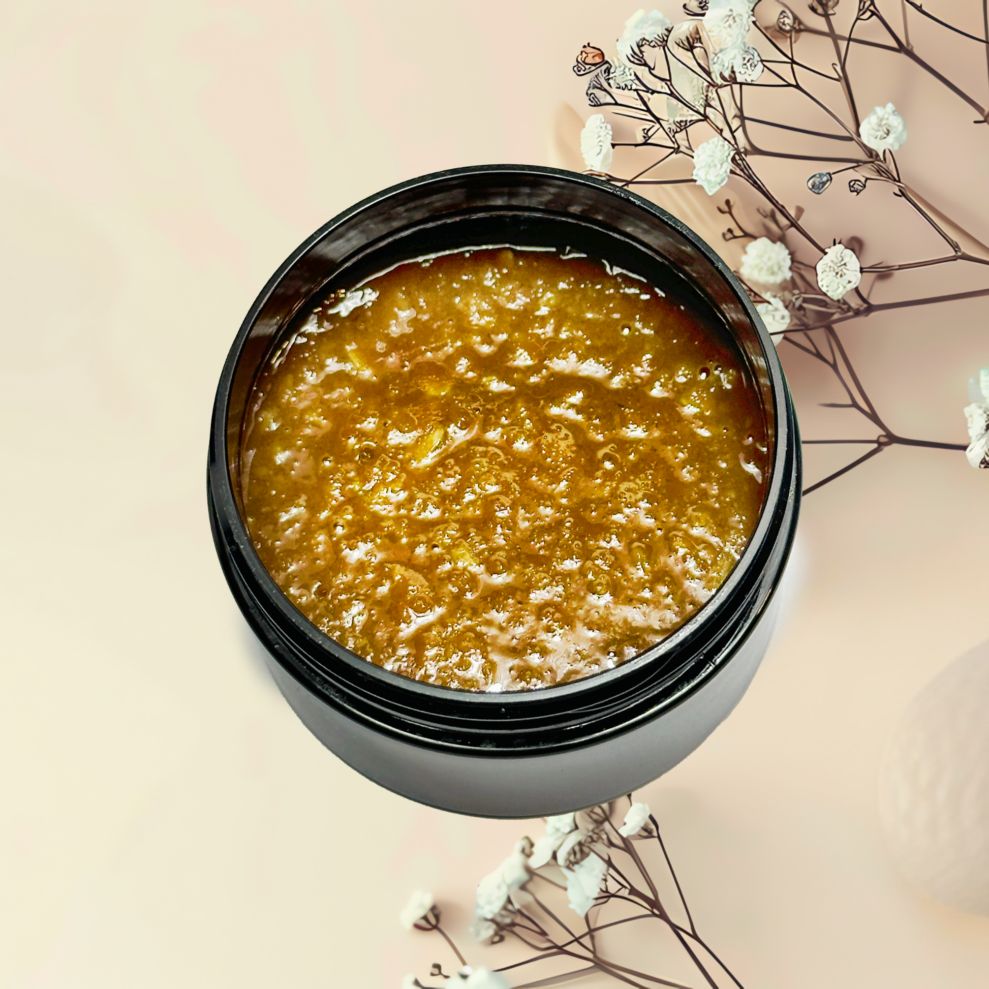 Jar of brown scrub with white flowers on a beige background