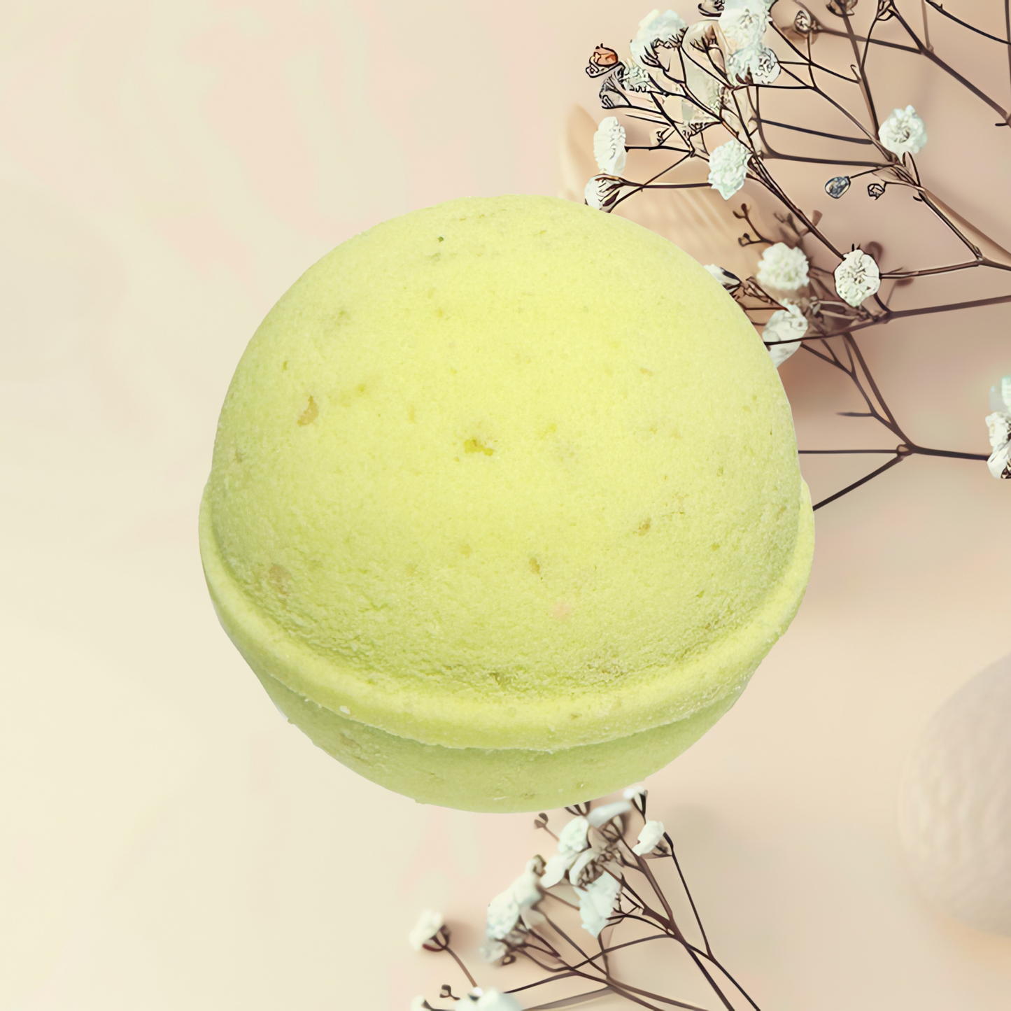 Green bath bomb with dried flowers on a light pink background