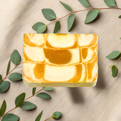 Marble-patterned soap bar with green leaves on a beige fabric background