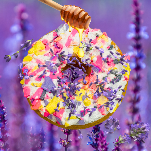 Colorful donut with sprinkles and honey drizzle on a background of lavender flowers