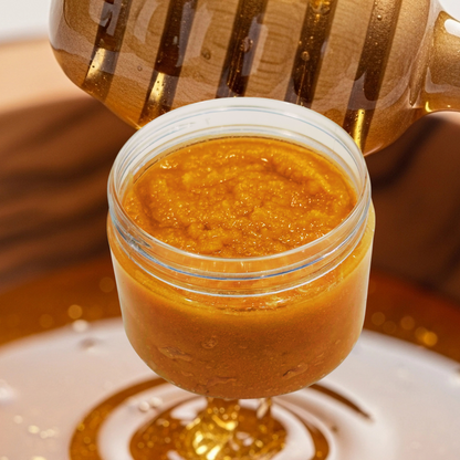 Jar of sugar scrub with a honey dipper on a wooden surface