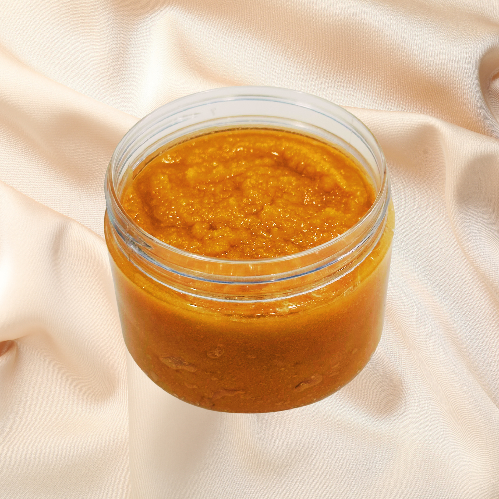 Jar of brown scrub on a beige fabric background