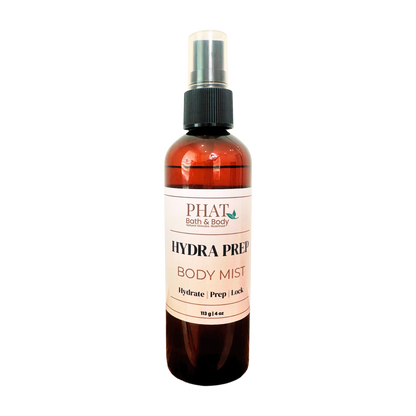 An amber spray bottle of PHAT Bath & Body Hydra Prep Body Mist with a black spray cap and a white label, shown on a plain white background.