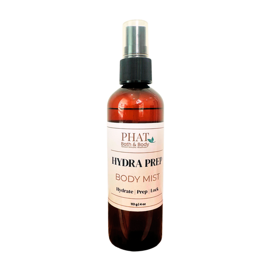 An amber spray bottle of PHAT Bath & Body Hydra Prep Body Mist with a black spray cap and a white label, shown on a plain white background.