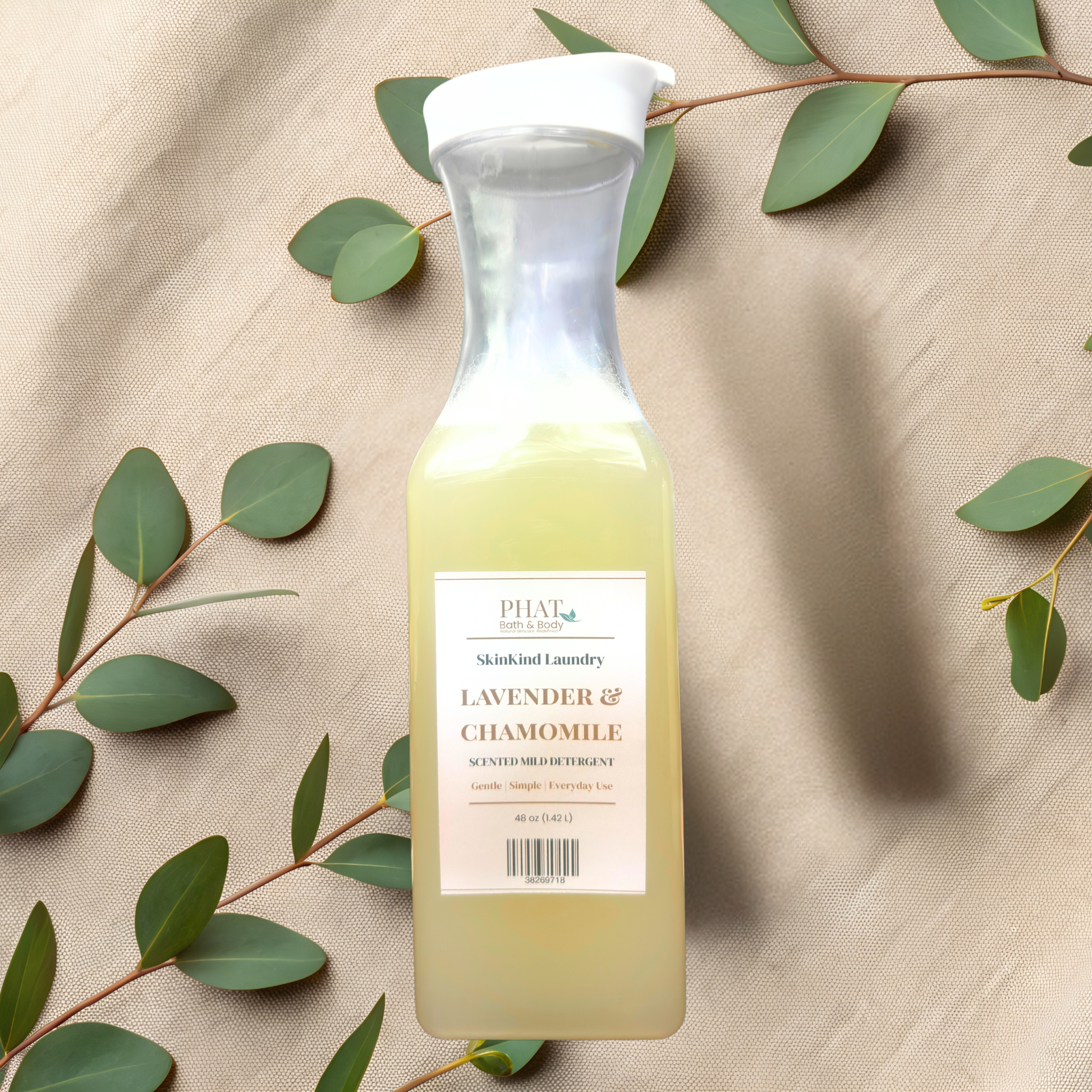 Bottle of Phat Bath & Body laundry detergent with green leaves on a beige fabric background