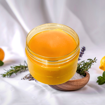 Jar of orange muscle rub on a white background with herbs and oranges