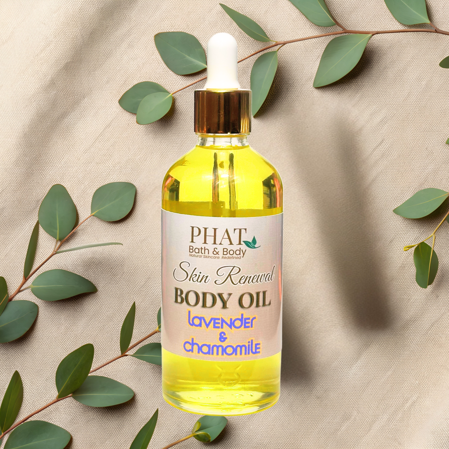 Bottle of PHAT Bath & Body Skin Renewal Body Oil with green leaves on a beige fabric background
