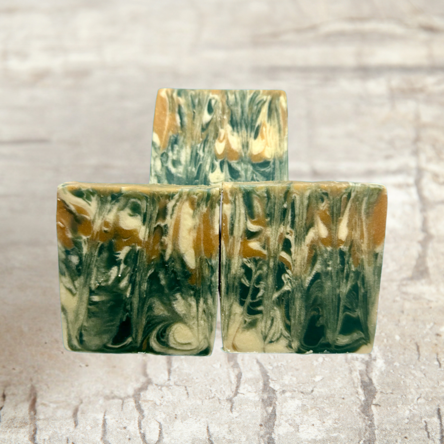 Three marbled soap bars with green and brown hues on a textured beige background