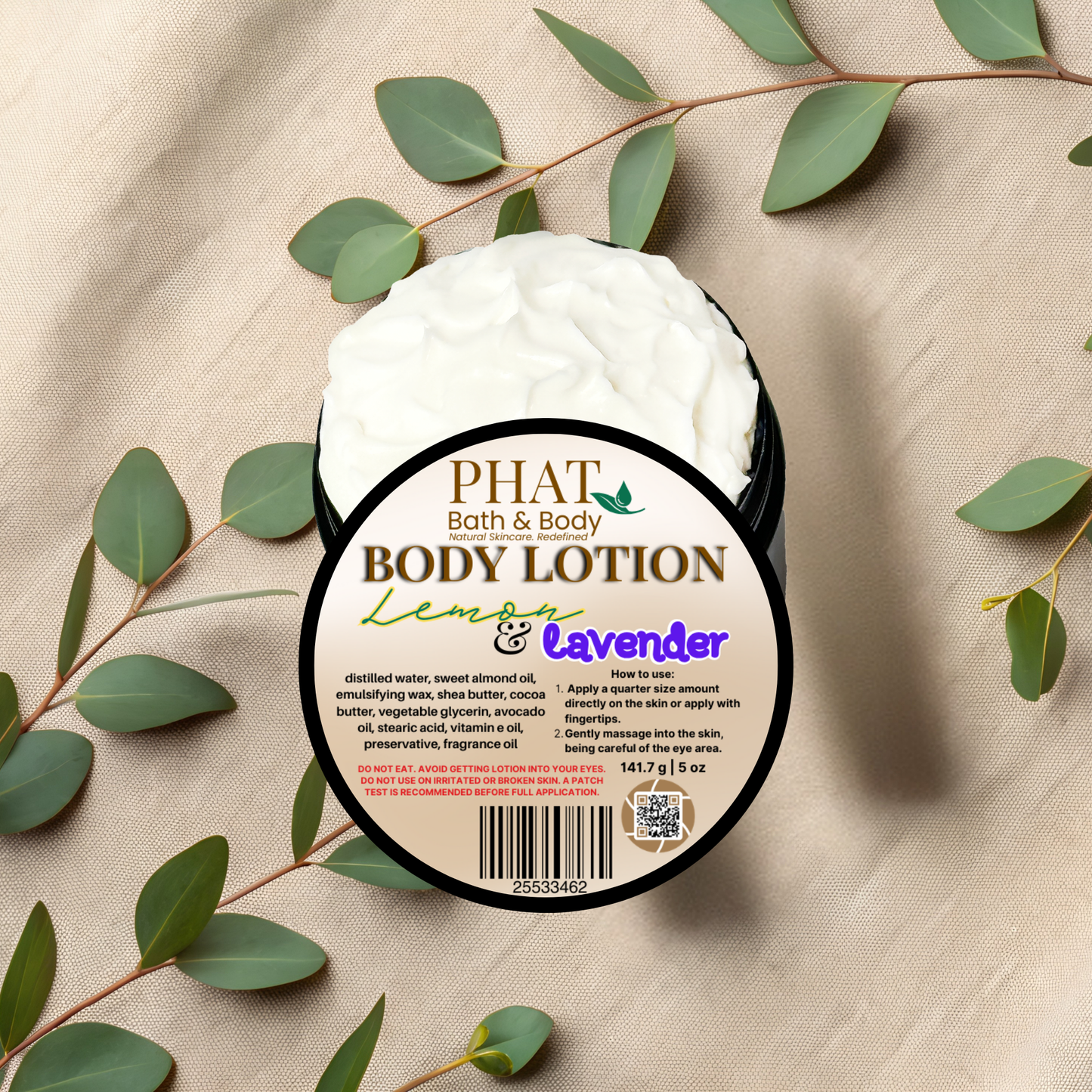 Body lotion container with 'Phat Bath & Body' label on a beige fabric background with green leaves.
