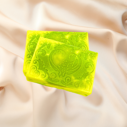 Two green soap bars with decorative patterns on a beige fabric background