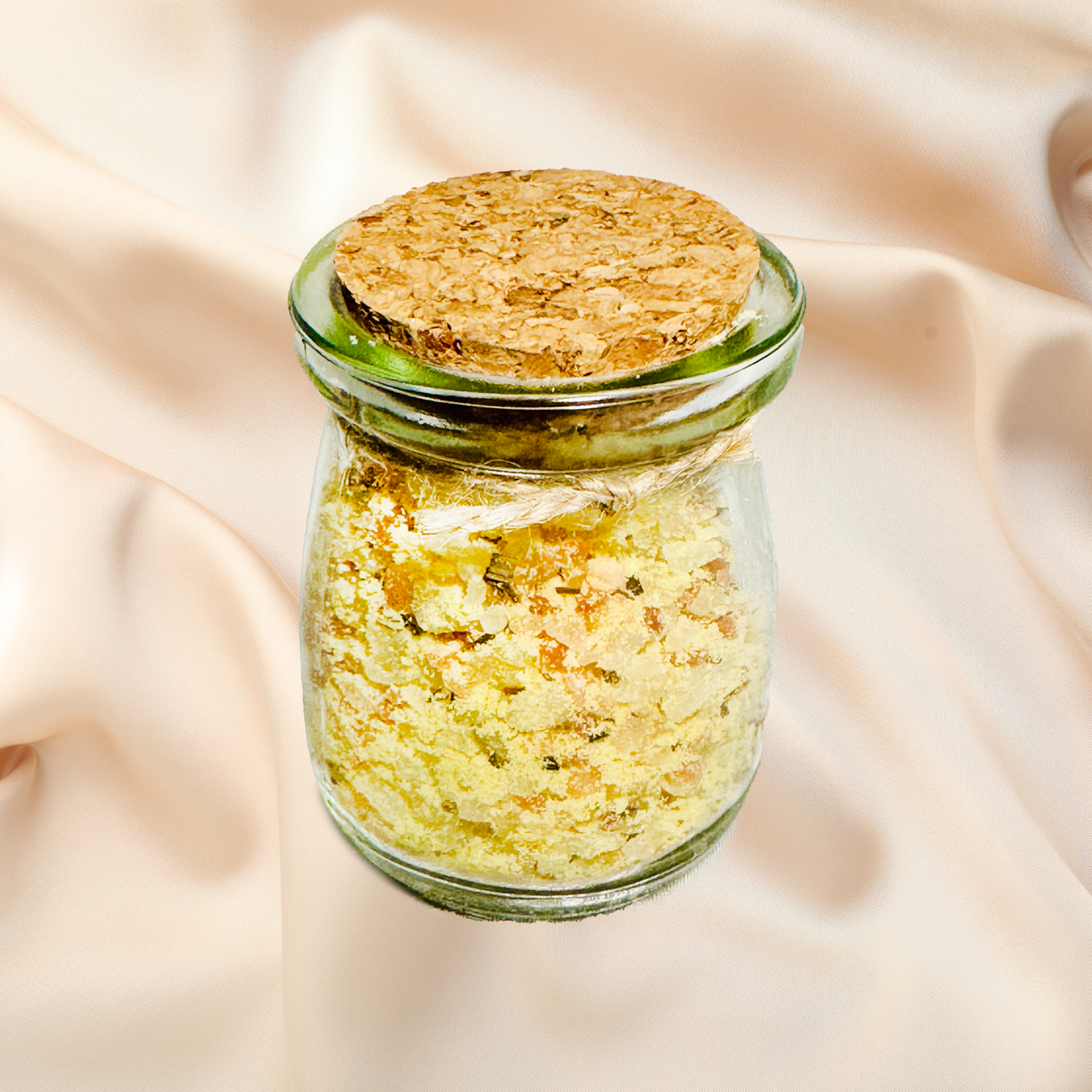 Glass jar with cork lid containing yellow bath salts on a beige fabric background