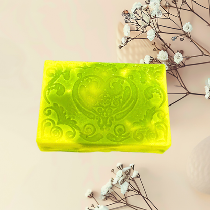 Yellow soap bar with embossed design on a light pink background with white flowers.