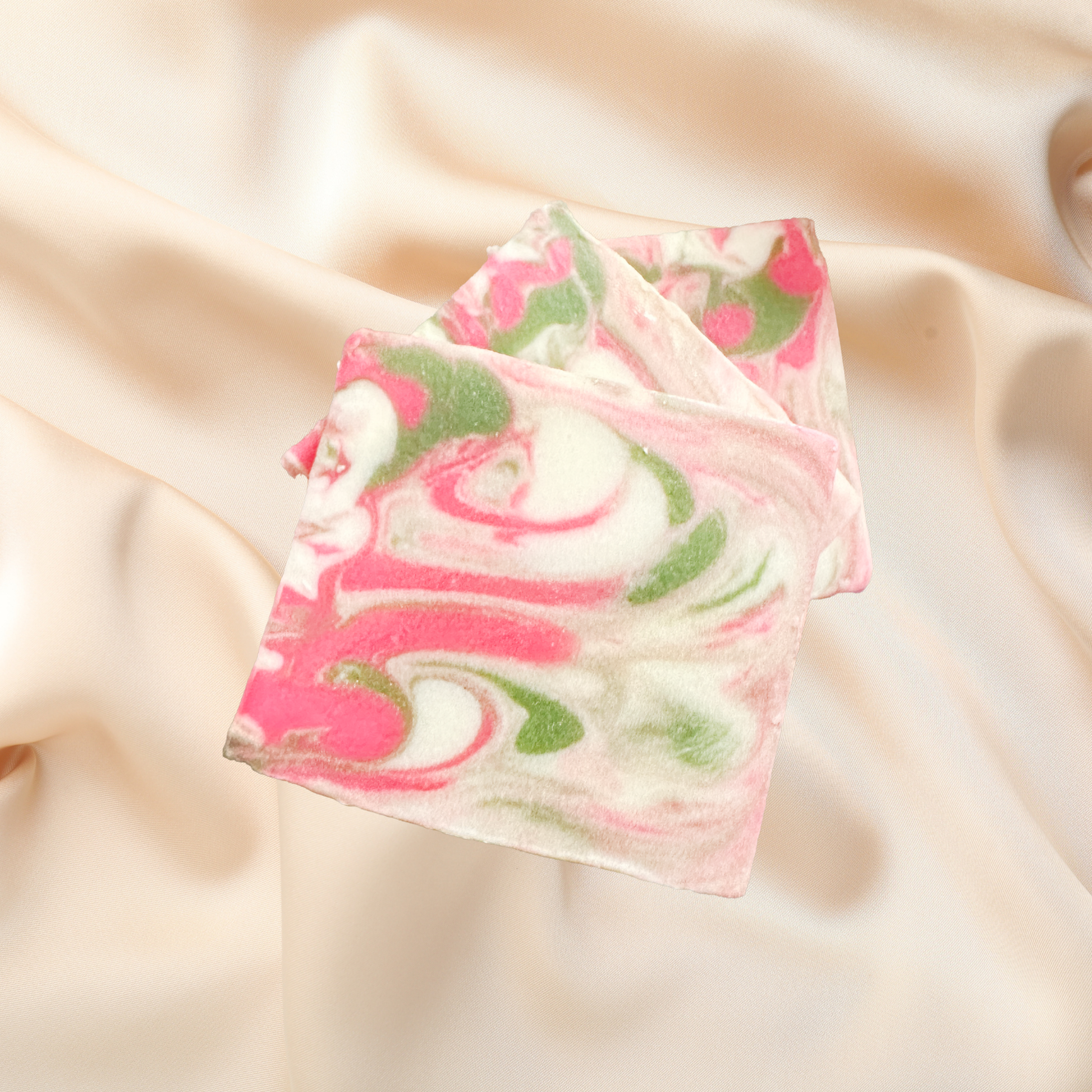 Marbled soap bar with pink and green swirls on a beige fabric background