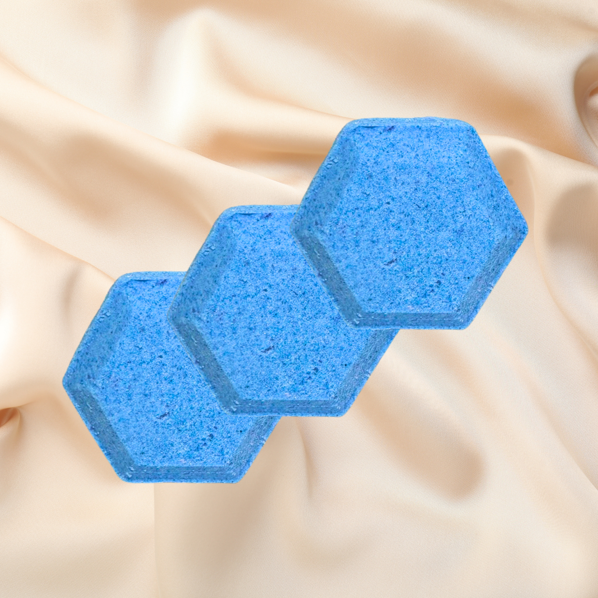 Two blue hexagonal shower bombs on a beige fabric background