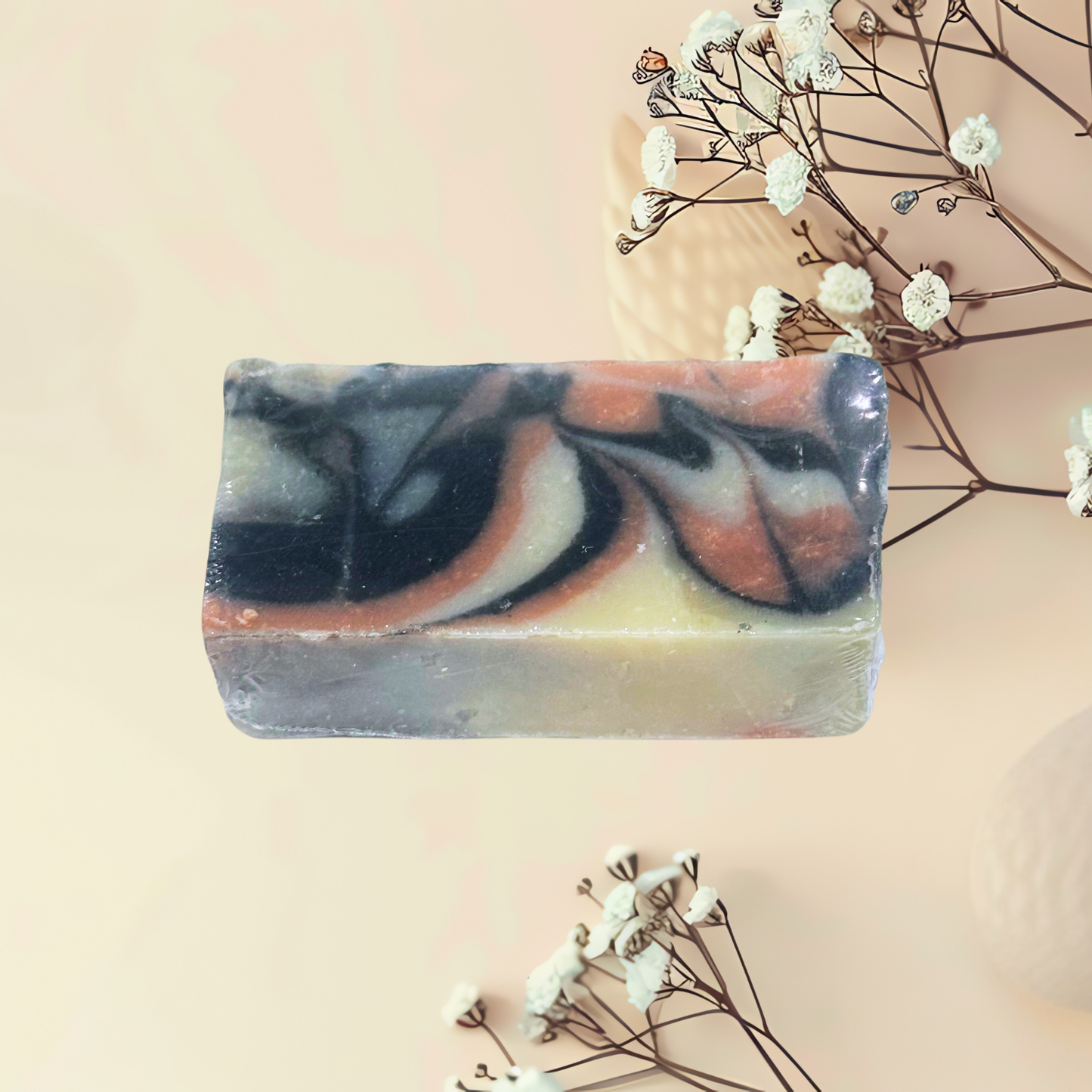 Handcrafted soap with zebra pattern on a light pink background with dried flowers.
