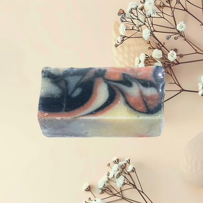 Handcrafted soap with zebra pattern on a light pink background with dried flowers.