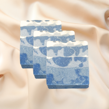 Three blue and white marbled soap bars on a beige fabric background