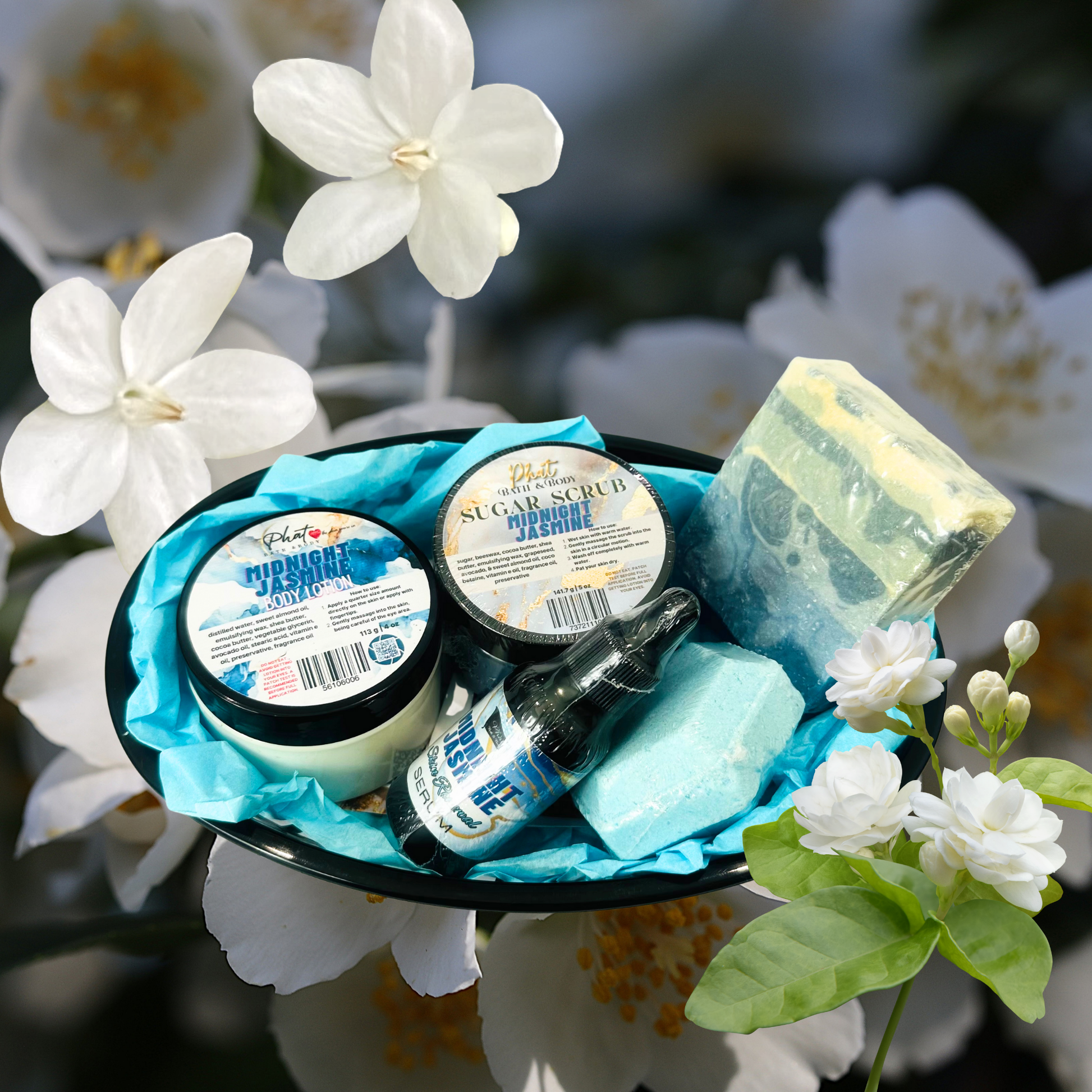 Assorted beauty products including jars, bottles, and a bar of soap on a blue cloth with white flowers in the background.