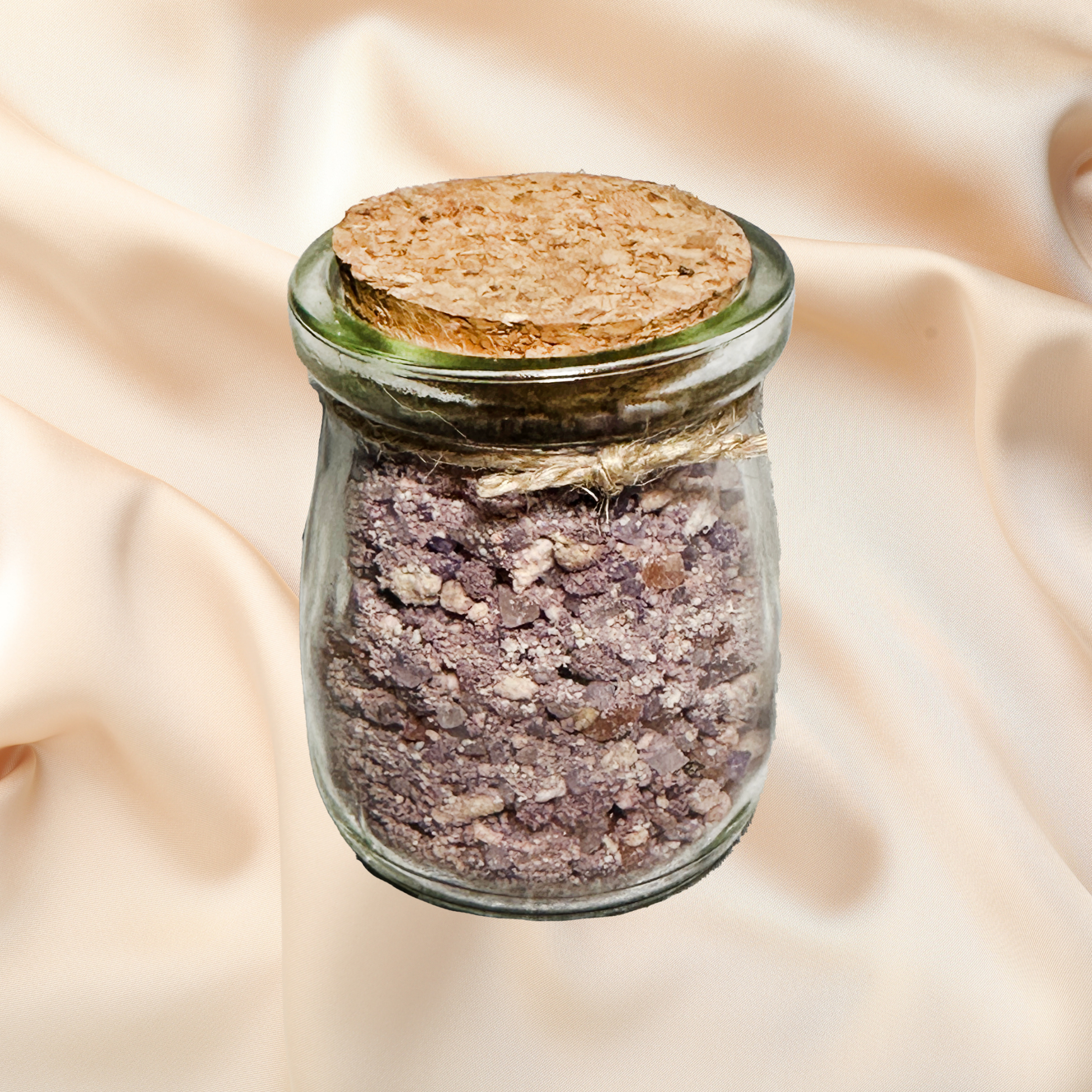 Glass jar with cork lid containing a purple bath salt mix on a beige fabric background